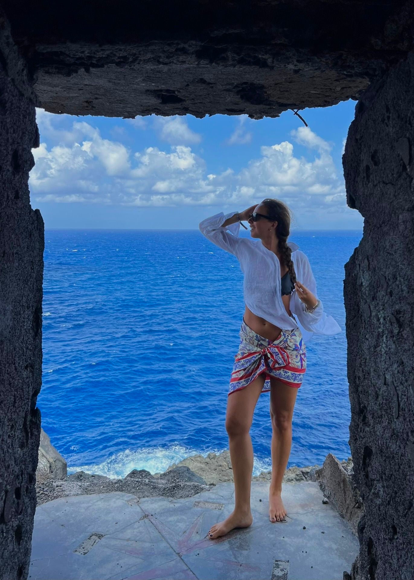 Woman wearing the Rubino red and blue silk scarf wrapped as a skirt in Sicily — bold Italian silk twill scarf styled for coastal elegance.